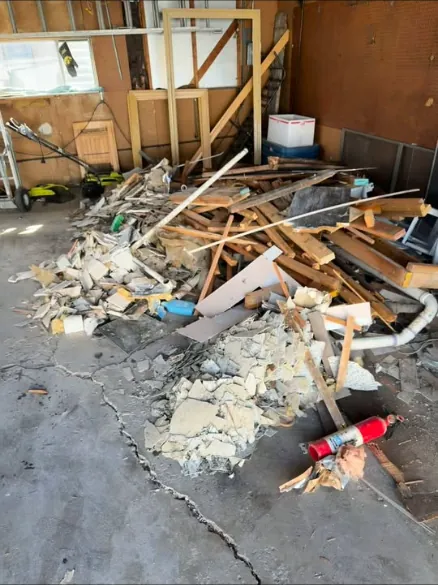 Pile of broken drywall, lumber and remodel debris on a garage floor